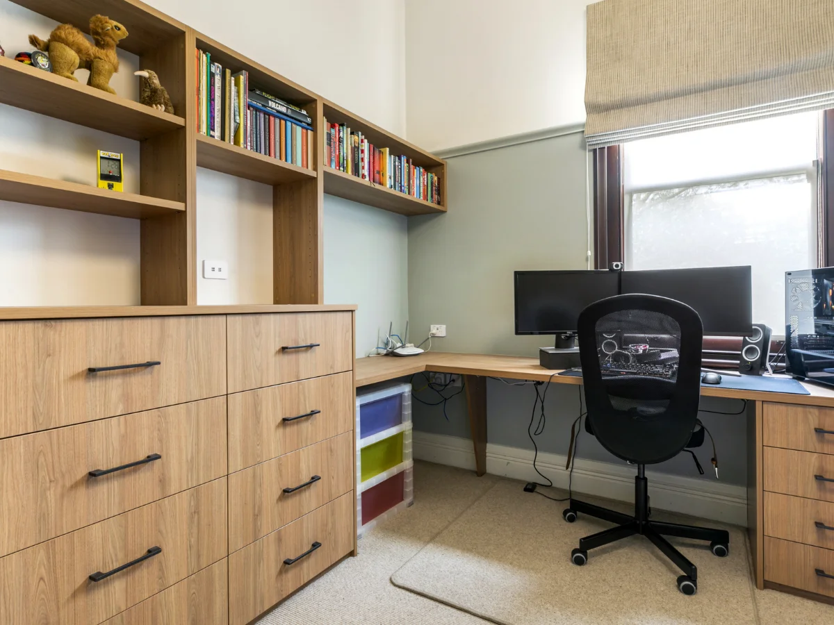 Ergonomic custom built-in desks with tailored wooden cabinetry, integrated task lighting, and floating overhead storage in a modern home office.